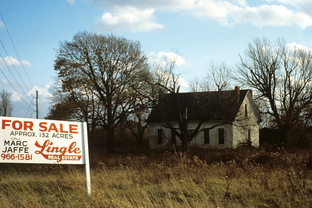 A rural Southern Indiana property with a For Sale sign in the front field