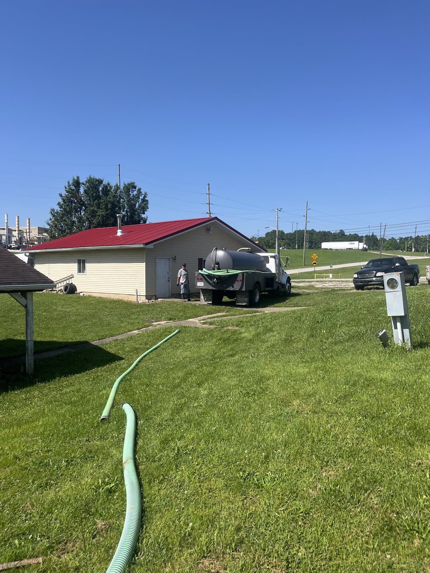 The Quick Pump and Clean tank truck parked beside a house with the suction hose running across the lawn toward the septic tank